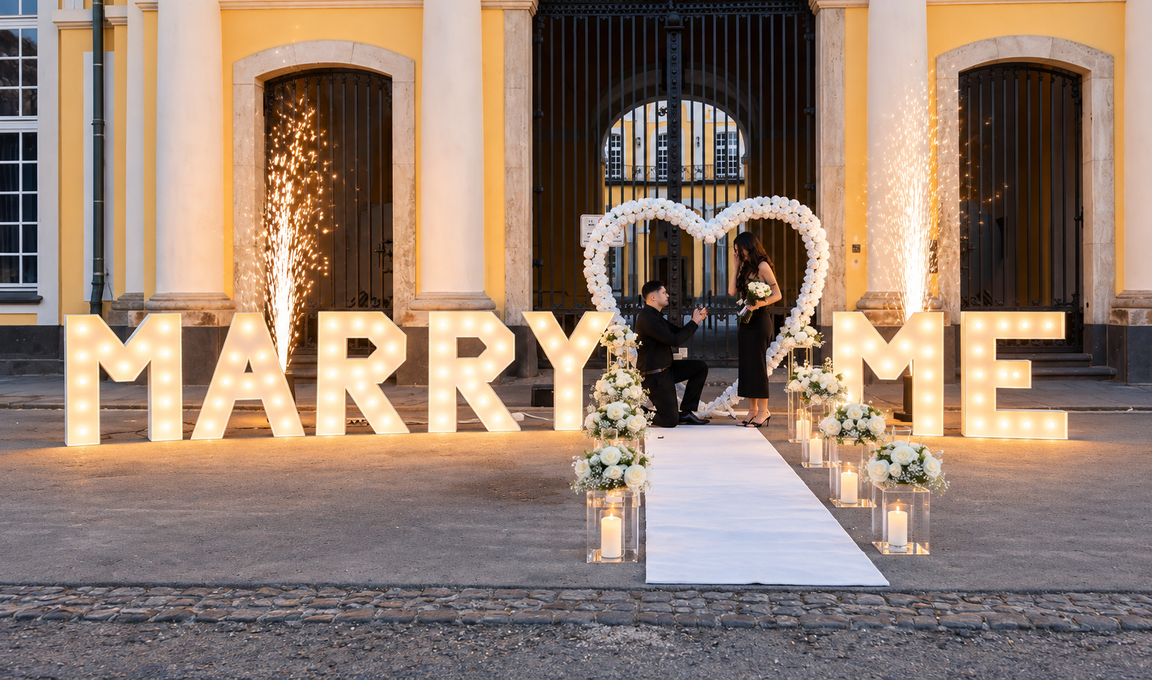 Antrag in Bonn mit weißem Rosenherz, Fontänen und leuchtenden Marry-Me-Buchstaben